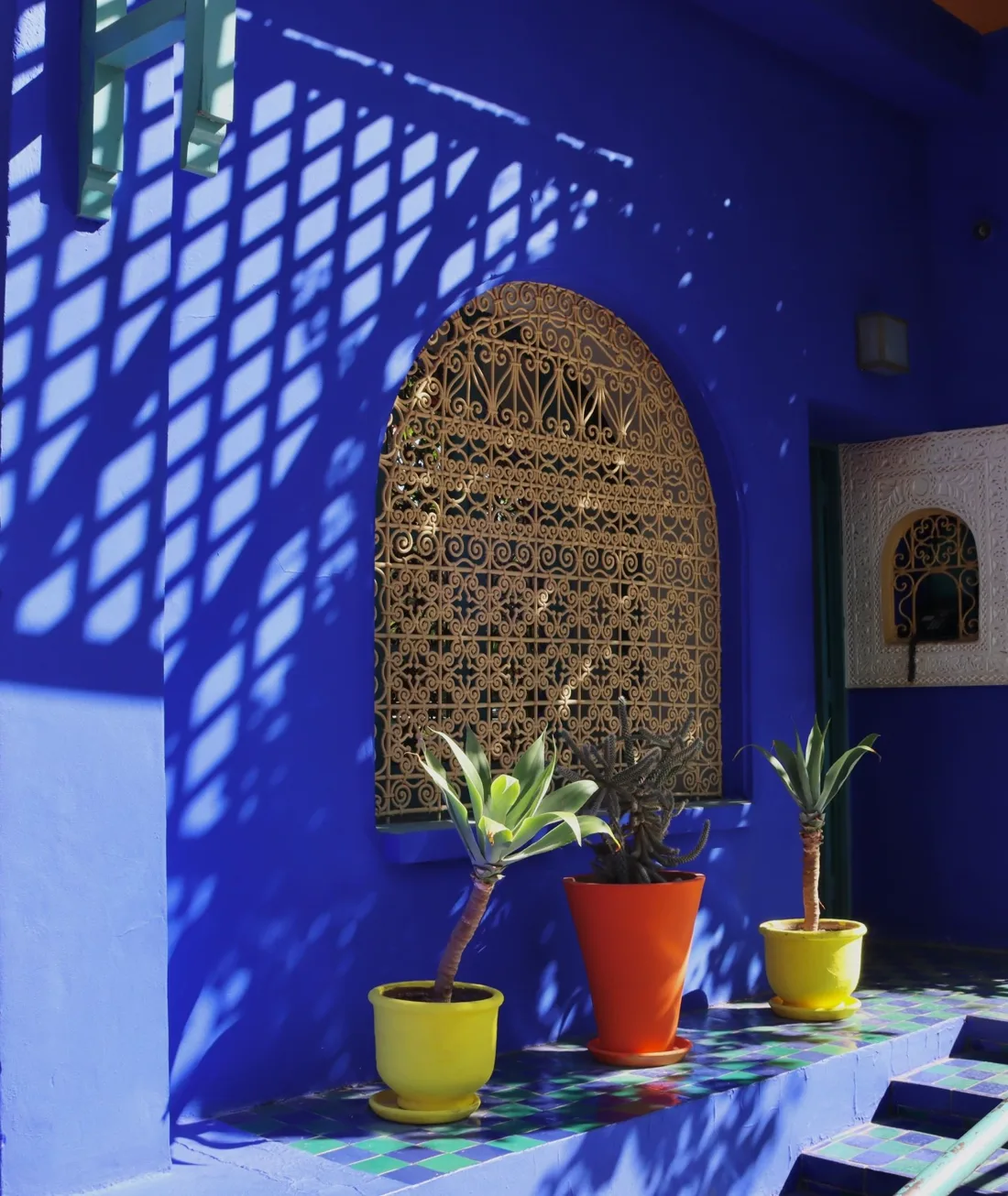 Une fenêtre en bois sculpté sur un mur bleu Majorelle