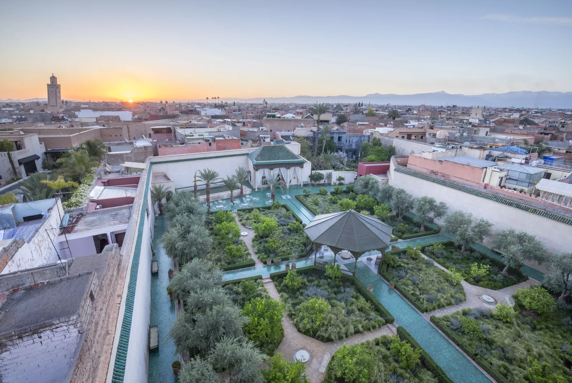 Le Jardin Secret vu d'en haut au coucher du soleil, ses quatre parterres et un minaret à l'horizon